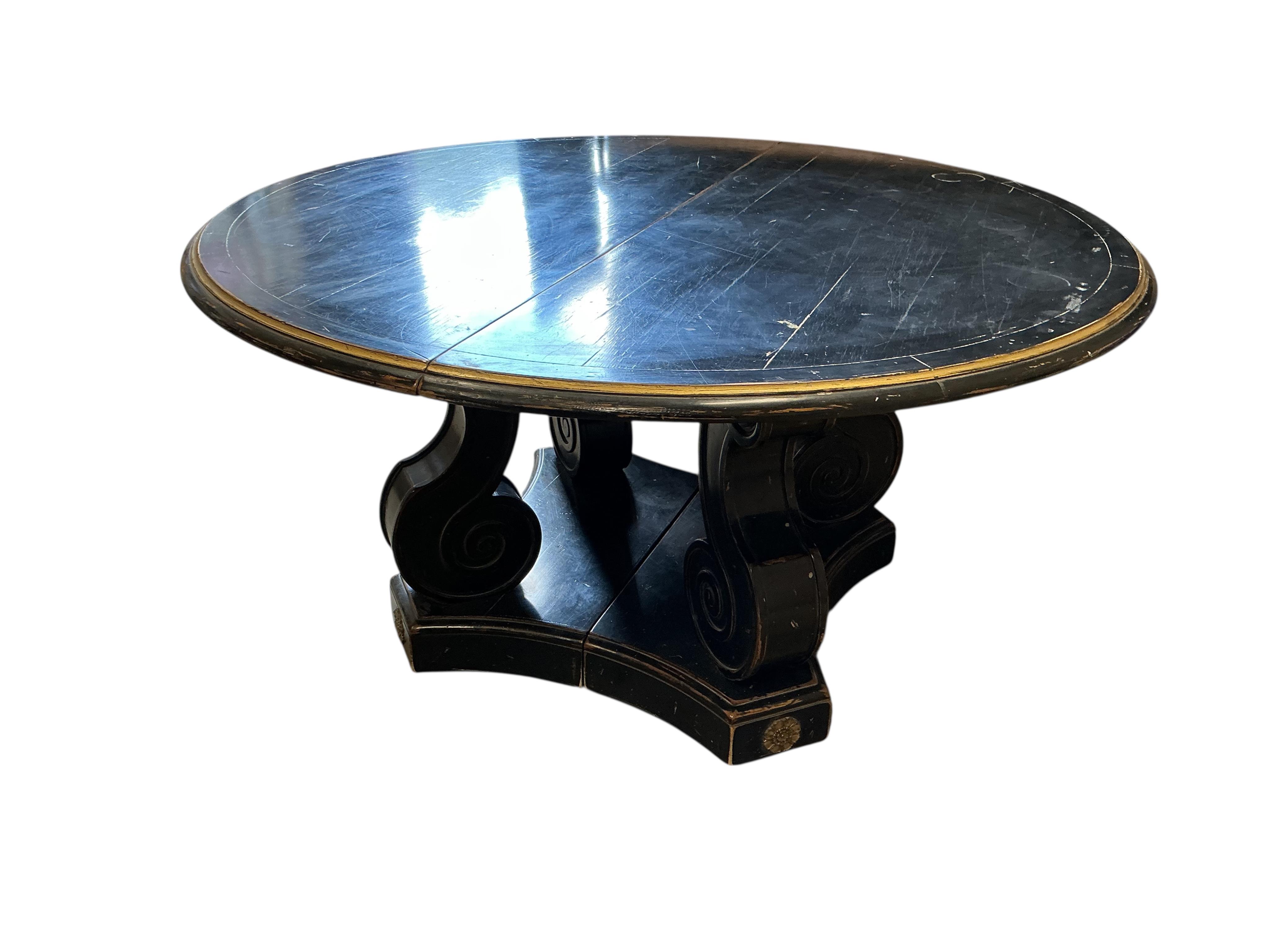 A Regency style ebonised, parcel gilt extending dining table, purchased from Liberty, diameter 150cm, 305cm extended three spare leaves, height